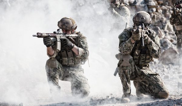 Team squad of special forces in action in the desert among the rocks covered by smoke screen